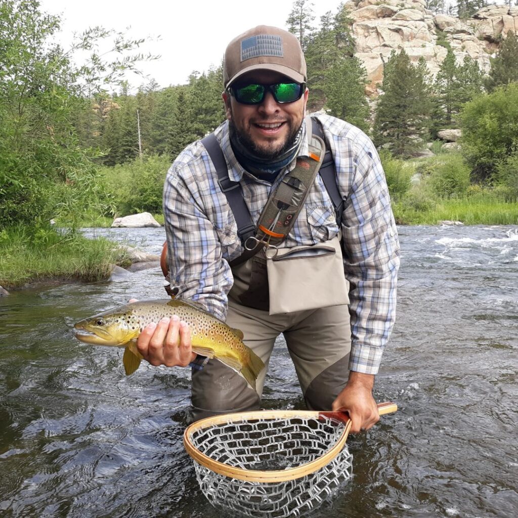 Carlos holding a brown trout that he caught.
